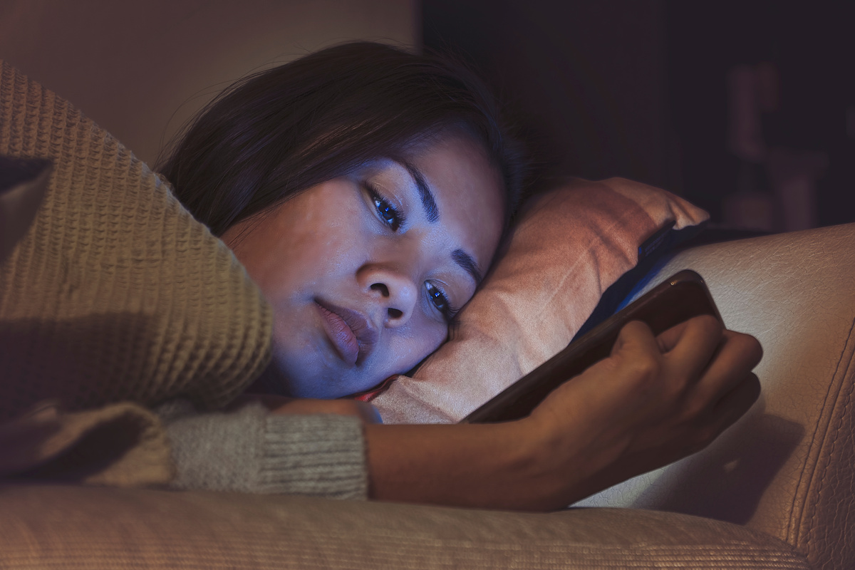 Asian woman using mobile phone in bed before sleep